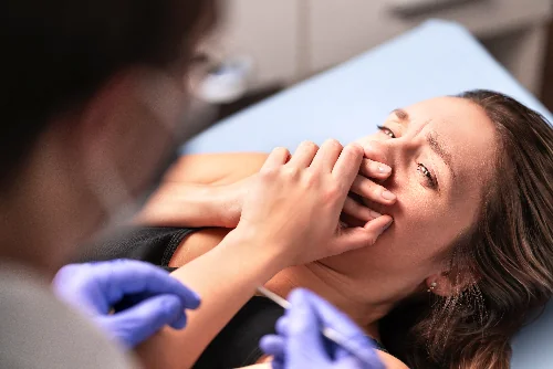 patient in pain in a dental chair holding her mouth after dental implant procedure