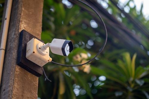 A security camera mounted outdoors captures the environment, showcasing technology for safety and surveillance in residential or urban areas.