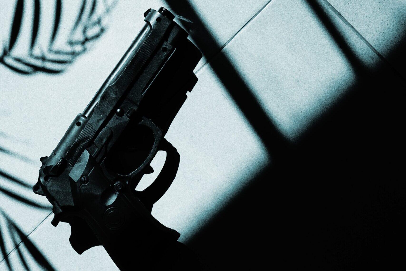 gun laying on the ground in the shadow of a window