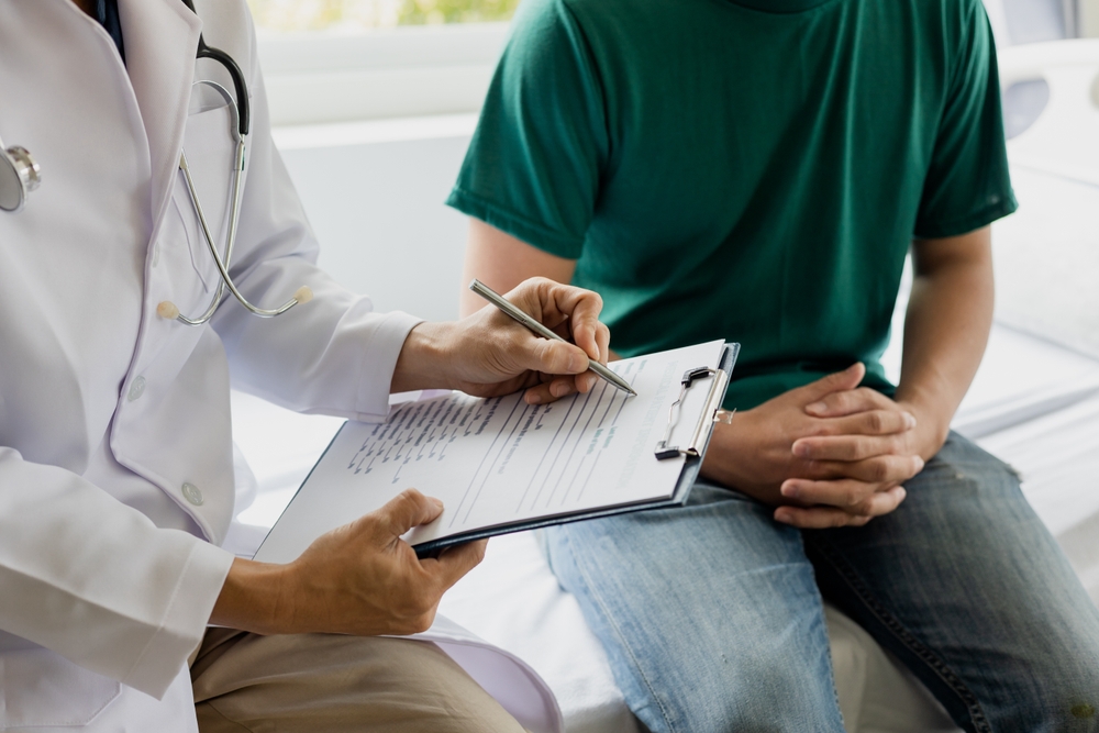 Doctor writing on a clipboard while talking with a patient during evaluation at a Florida psychiatric facility.